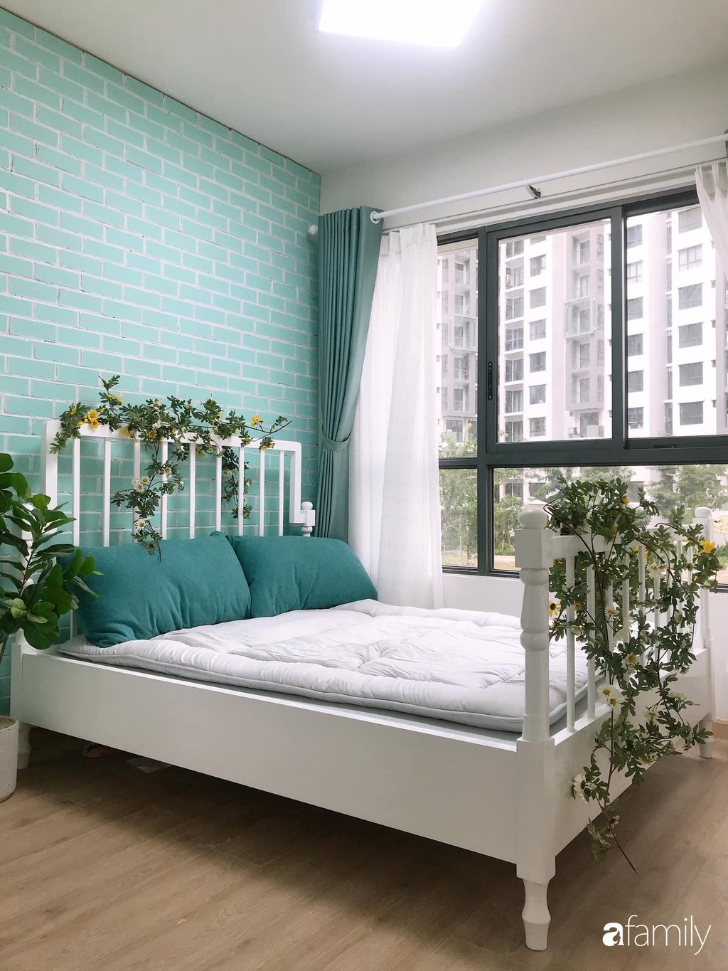 Điểm tô trên chiếc giường trắng là những cành hoa cúc rủ tạo vẻ đẹp ngọt ngào và lãng mạn cho không gian nghỉ ngơi. Cách lựa chọn màu sắc đơn giản, nội thất gọn gàng giúp không gian thêm rộng và thoáng hơn nhiều so với diện tích thực.