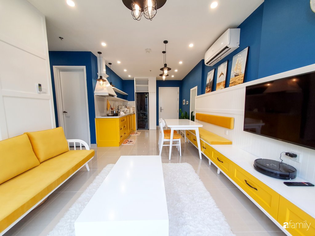 Khoảng tường đối diện với sofa được sơn màu vàng kết nối với bức tường phòng ăn và bếp nấu. Sự liên kết màu sắc tạo nên sự hài hòa về tổng thể cũng như tạo cảm giác ưa nhìn cho từng không gian nhỏ.