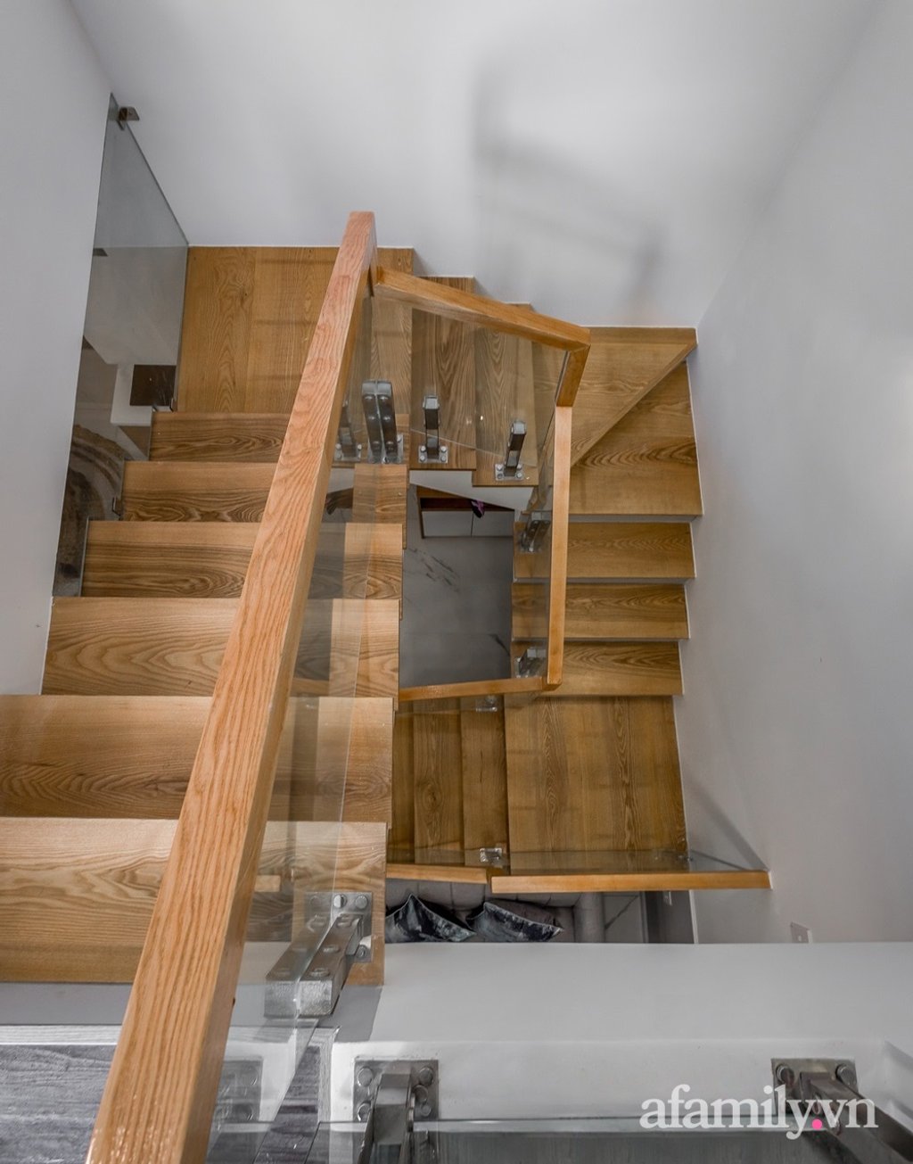 Cầu thang gỗ với lan can kính mang ánh sáng và sự thông thoáng vào nhà.