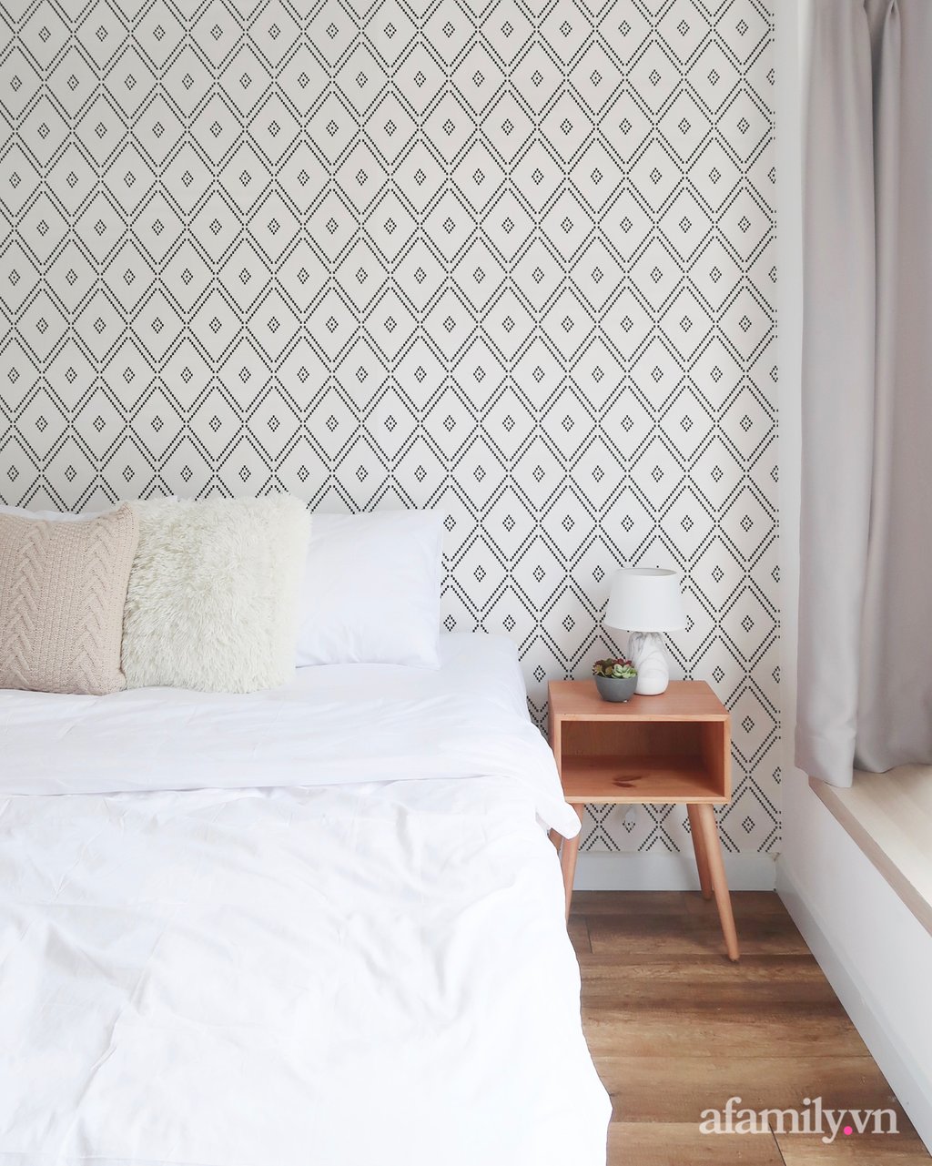 Phòng ngủ với tông màu trắng cơ bản. Những chiếc gối bông êm ái và giấy dán tường hoa văn được sử dụng làm điểm nhấn cho không gian.